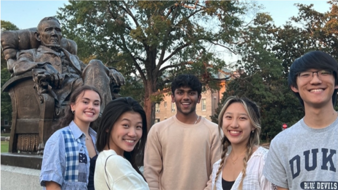 students on East Campus in front of statue