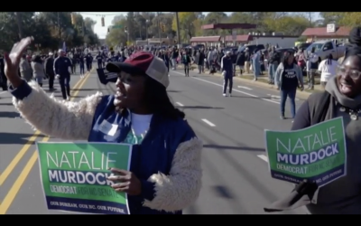 Natalie Murdock holding a campaign sign and marching in a parade