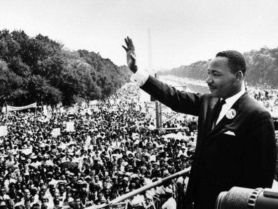 black and white photo of MLK Jr. waving at his to crowd in Washington D.C.
