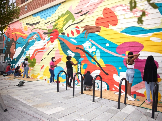A group of people paint a colorful mural together