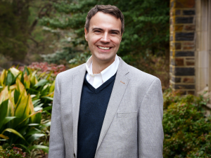 A man wearing a gray jacket and smiling