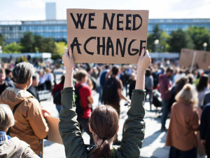 person holding sign that says "we need a change"