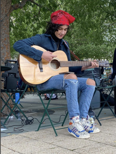 Elliott Loverin sitting outside playing guitar 