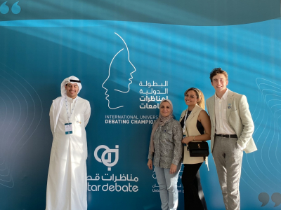 4 people posing together in front of a blue Arabic sign