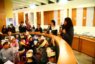 College students gather around a class of young school children wearing paper crowns